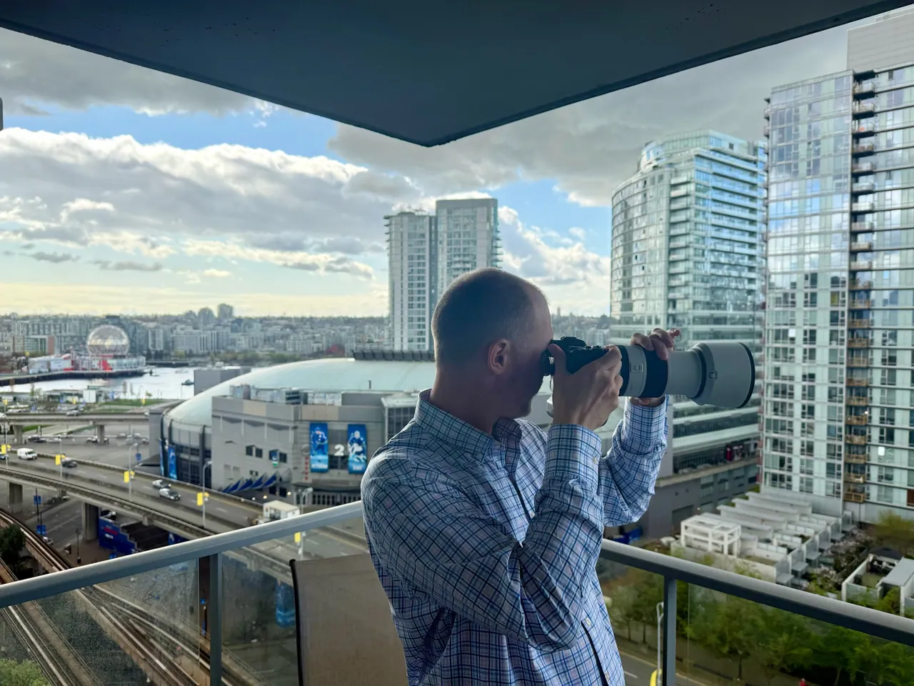 Photographer using a long lens from a balcony overlooking city buildings