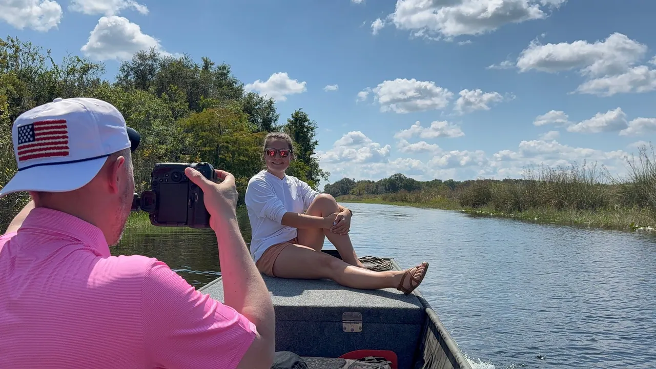 Photographer framing a seated subject on a boat in a tree-lined waterway