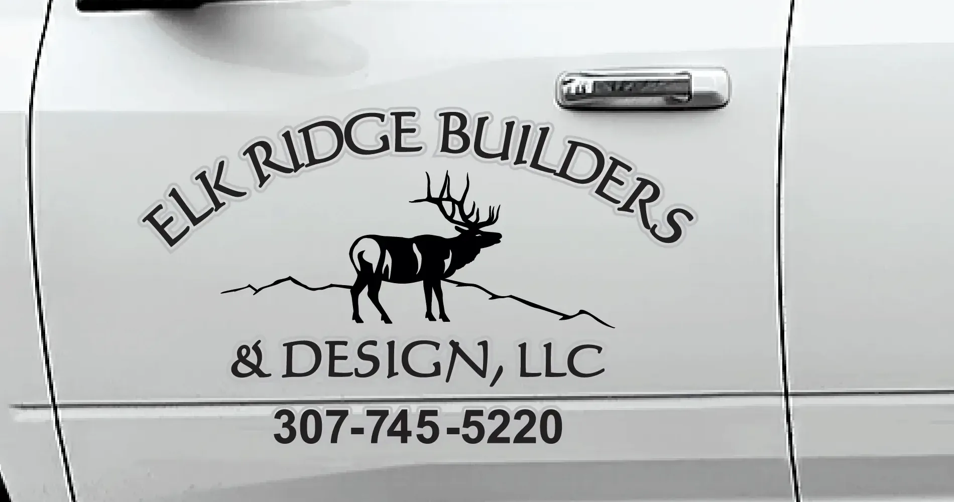 The Elk Ridge Builders door graphic Mondo designed: the arched wordmark over an elk-and-ridge mark, with the phone number beneath it, on the cab door of a white pickup.